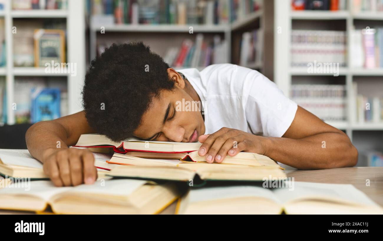 Fatigué guy sieste sur la pile de livres dans la bibliothèque Banque D'Images