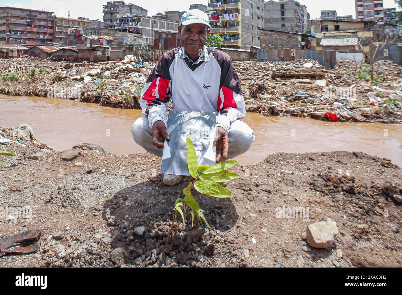 Nairobi, Kenya. 05 juin 2024. Le fondateur du Ghetto Farmers Mathare (GHM) Humphrey Omukuti, un collectif de résidents de Mathare qui travaillent ensemble dans l'agriculture en mettant l'accent sur la réhabilitation de la rivière Nairobi, tient un portrait de la lauréate du prix Nobel de la paix 2004, l'écologiste et militante des droits humains Wangari Maathai, avant un exercice de plantation d'arbres lors d'un événement organisé pour marquer la Journée mondiale de l'environnement 2024 dans le bidonville de Kiamaiko, à Nairobi, Kenya, le 05 juin 2024. Crédit : SOPA images Limited/Alamy Live News Banque D'Images