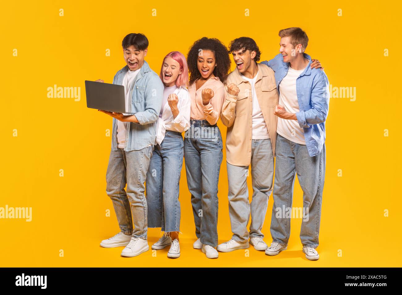 Groupe d'amis enthousiaste célébrant le succès avec Laptop Banque D'Images