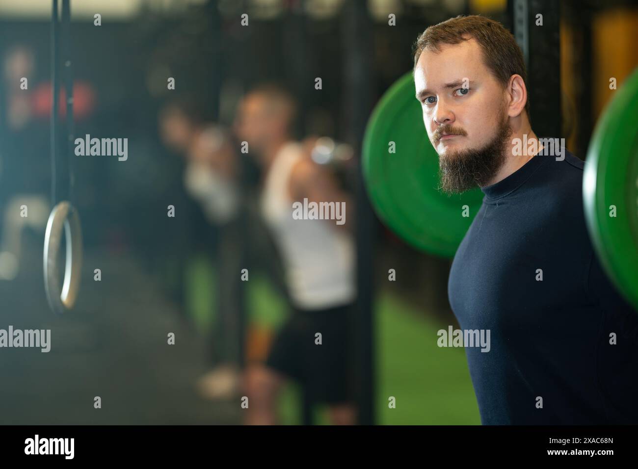 Homme barbu faisant des exercices avec barre pendant l'entraînement de groupe Banque D'Images