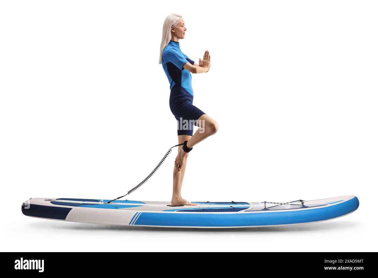 Plan de profil pleine longueur d'une femme exerçant le yoga sur une planche de paddle isolé sur fond blanc Banque D'Images