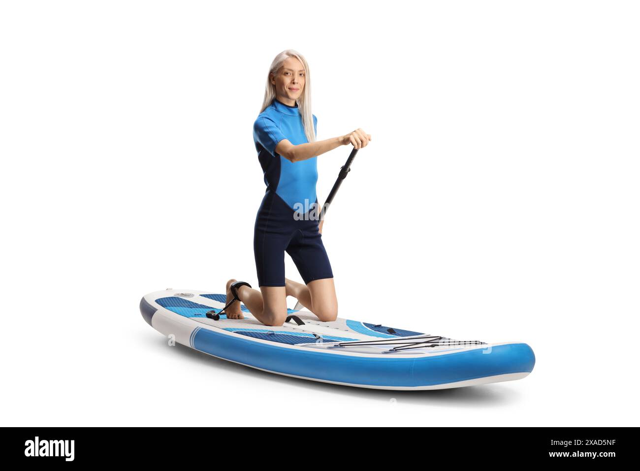 Femme dans une combinaison avec une pagaie agenouillée sur une planche de sup isolé sur fond blanc Banque D'Images