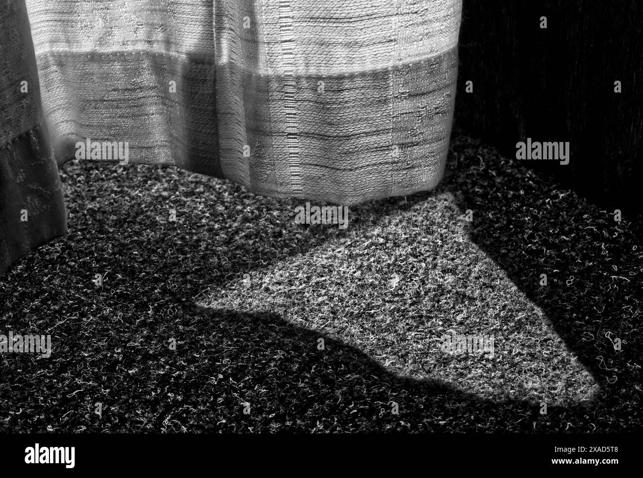 Détails de tissu de rideau et un tapis de feutre avec un triangle de lumière et quelques ombres en noir et blanc Banque D'Images