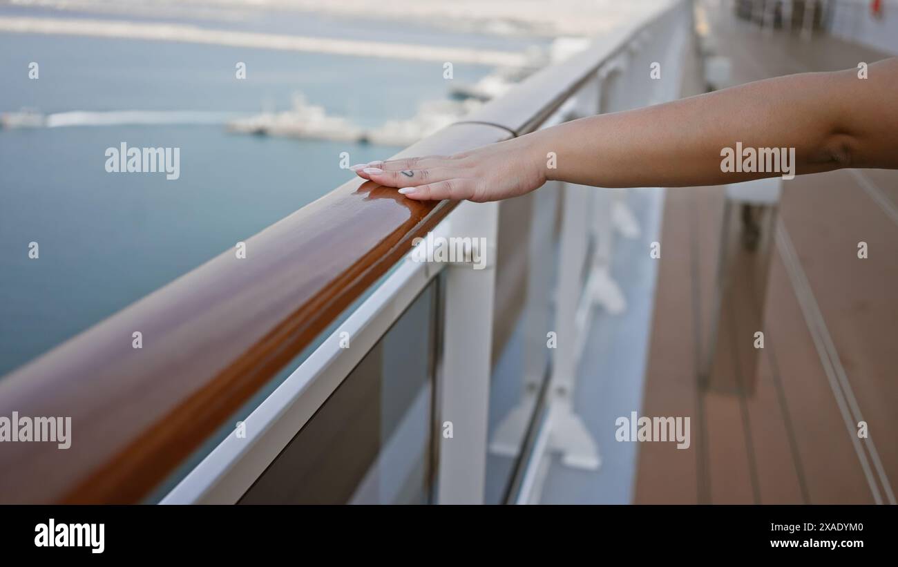 La main d'une femme reposant sur la balustrade d'un pont de bateau de croisière surplombant l'océan. Banque D'Images
