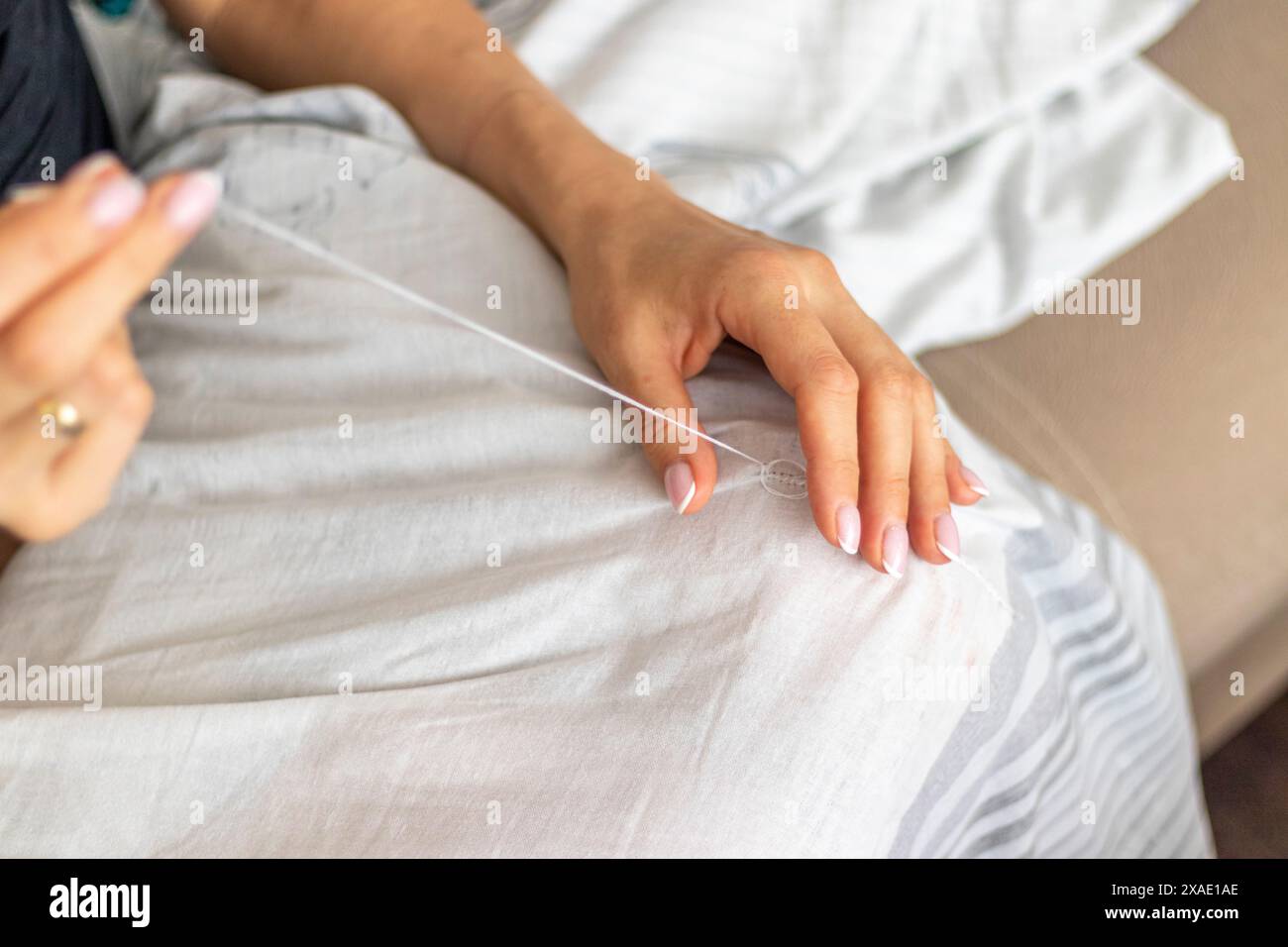 Plan de la femme avec de belles mains cousuant ou patchant un tissu de lin Banque D'Images