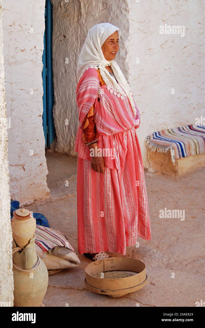 Femme berbère dans une maison troglodyte broyant du maïs, Matmata, Gouvernorat de Gabes, Tunisie Banque D'Images