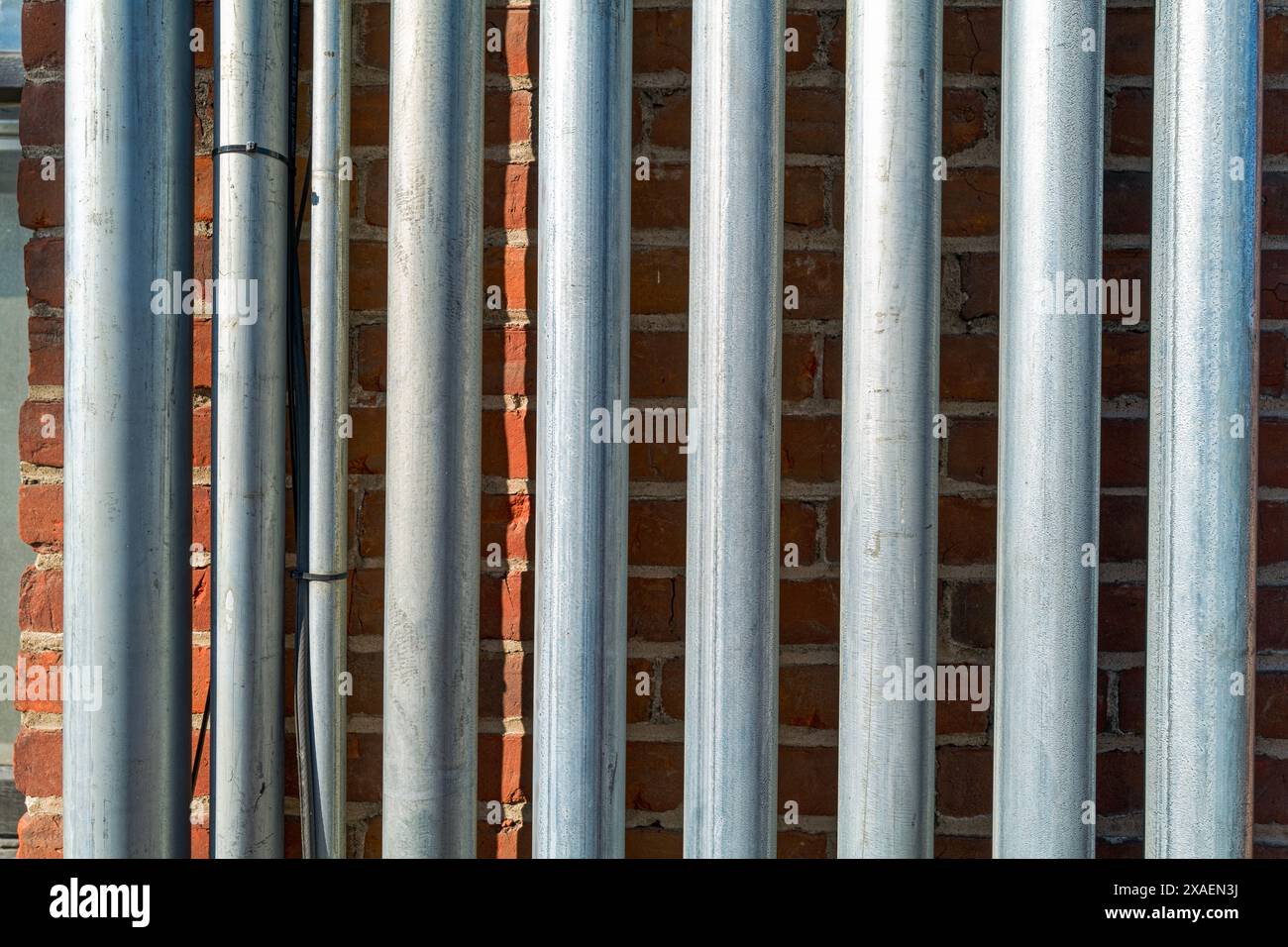 Détail des conduits métalliques montant et descendant en parallèle le long d'un mur extérieur de briques Banque D'Images