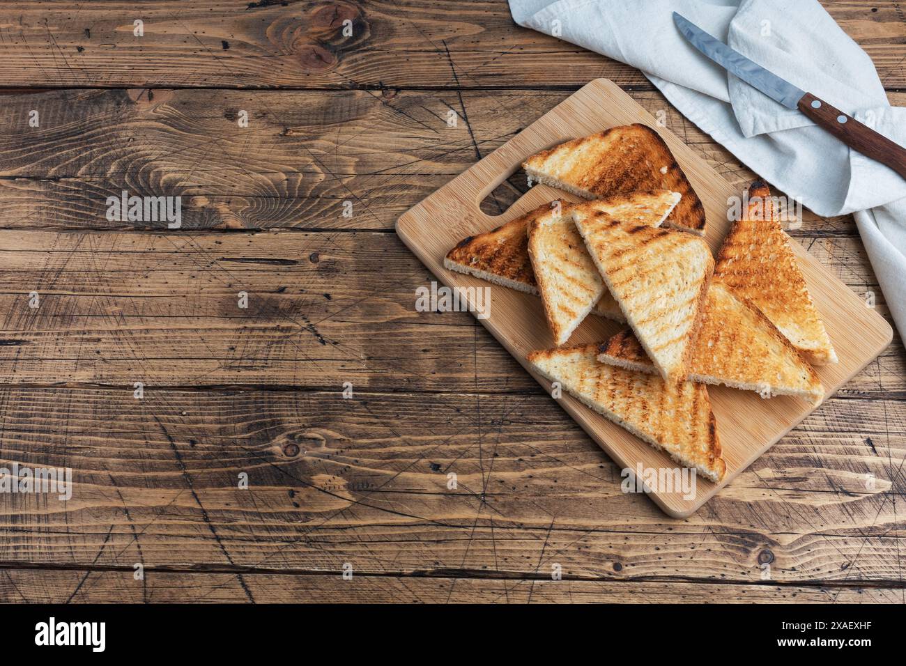 Tranches de pain grillé croustillant pour les sandwichs sur une planche à découper, fond rustique en bois. copier l'espace Banque D'Images Tranches de pain grillé croustillant pour les sandwichs sur une planche à découper, fond rustique en bois. copier l'espace Banque D'Images