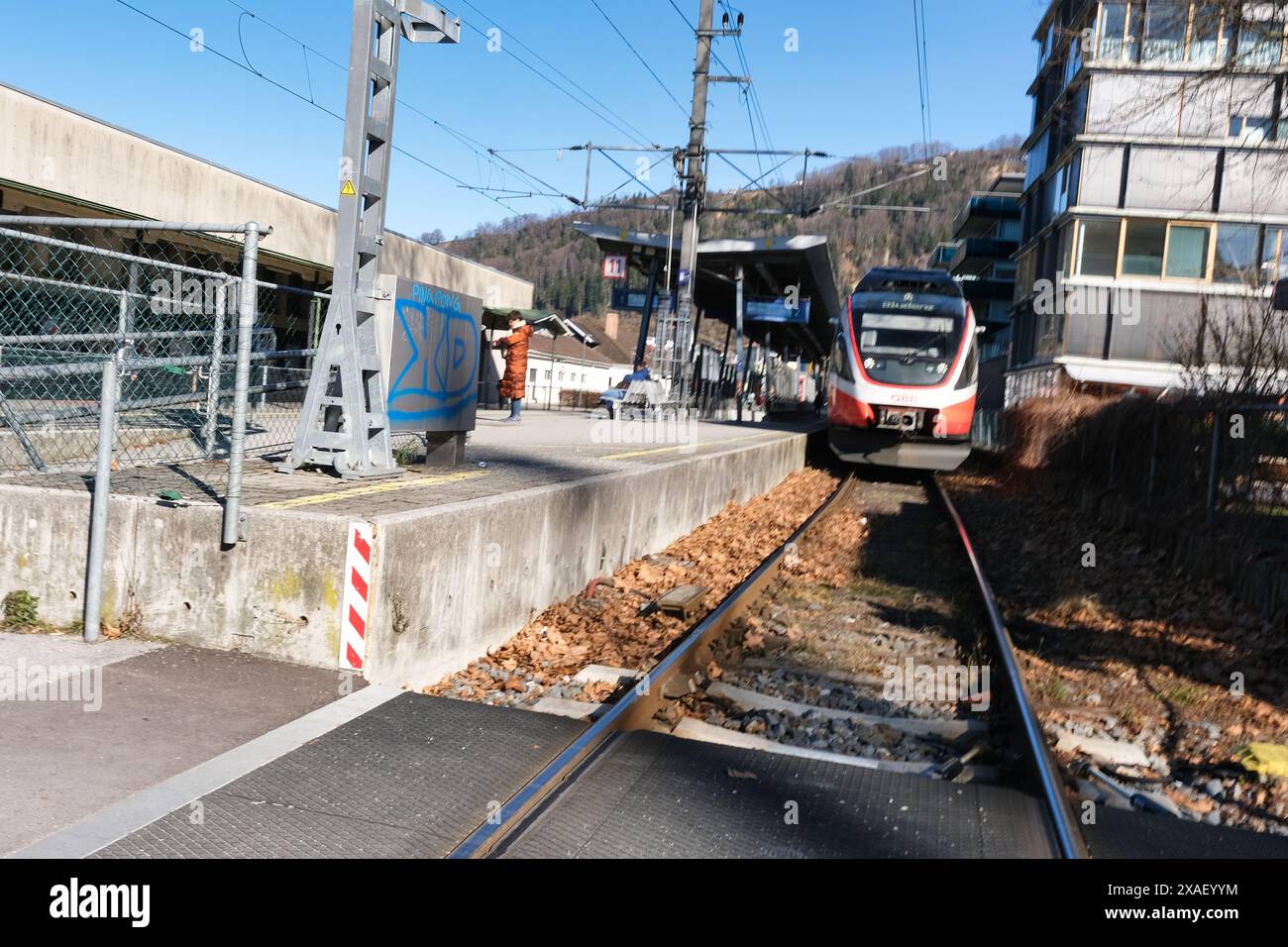 Un train est sur les rails devant un bâtiment. Le train est rouge et blanc Banque D'Images