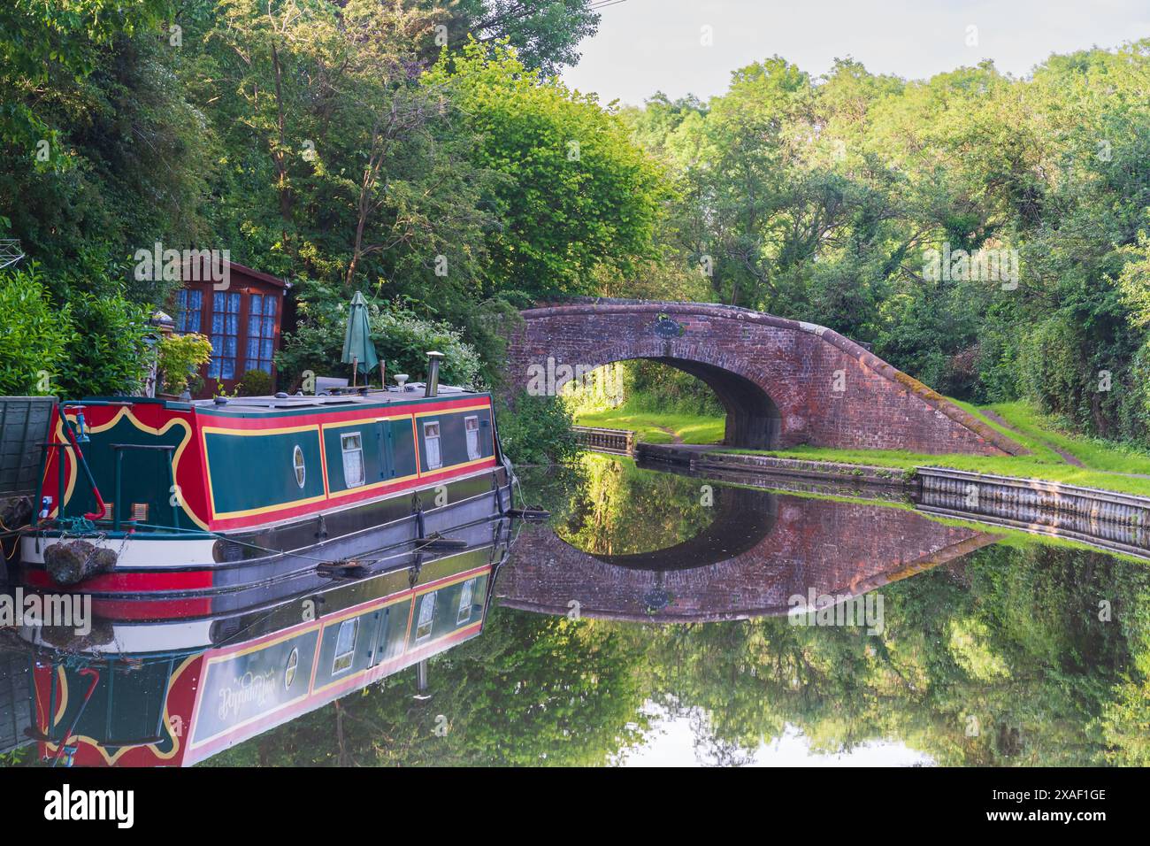 Un bateau de canal ou une barge amarrée sur l'eau avec un pont et un reflet derrière Banque D'Images