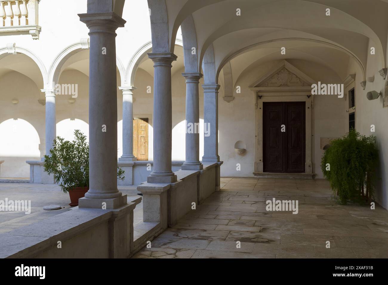 photo d'une cour intérieure d'un bâtiment baroque blanc avec colonnade et porte en bois sombre le jour ensoleillé Banque D'Images