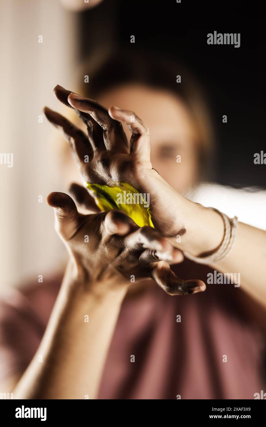 Artiste féminine faisant une peinture artistique avec ses mains. Fille mélangeant les couleurs et peignant les mains. Banque D'Images