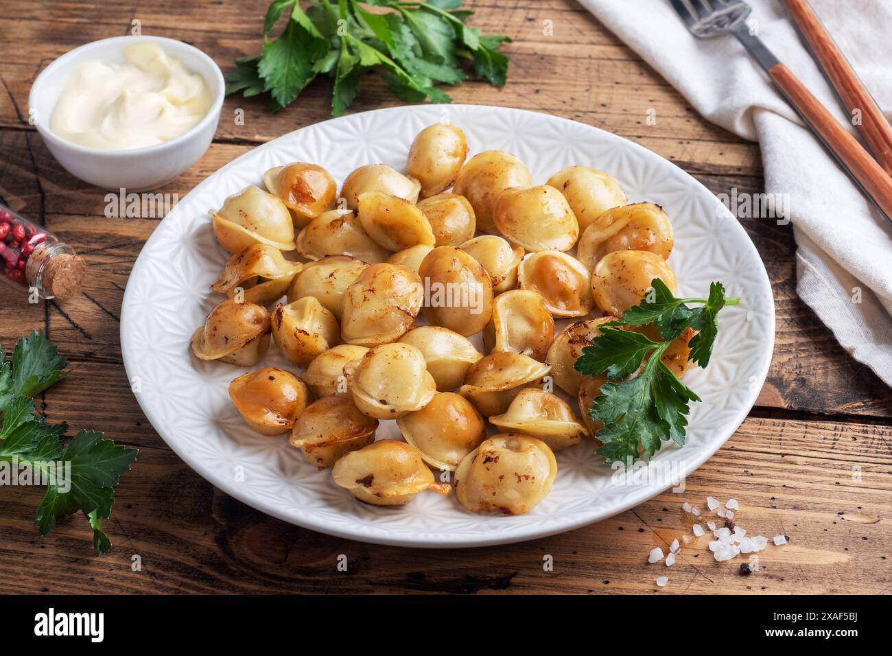 Pelmeni frit traditionnel, raviolis, boulettes fourrées de viande sur l'assiette, cuisine russe. Table rustique en bois, espace copie Banque D'Images