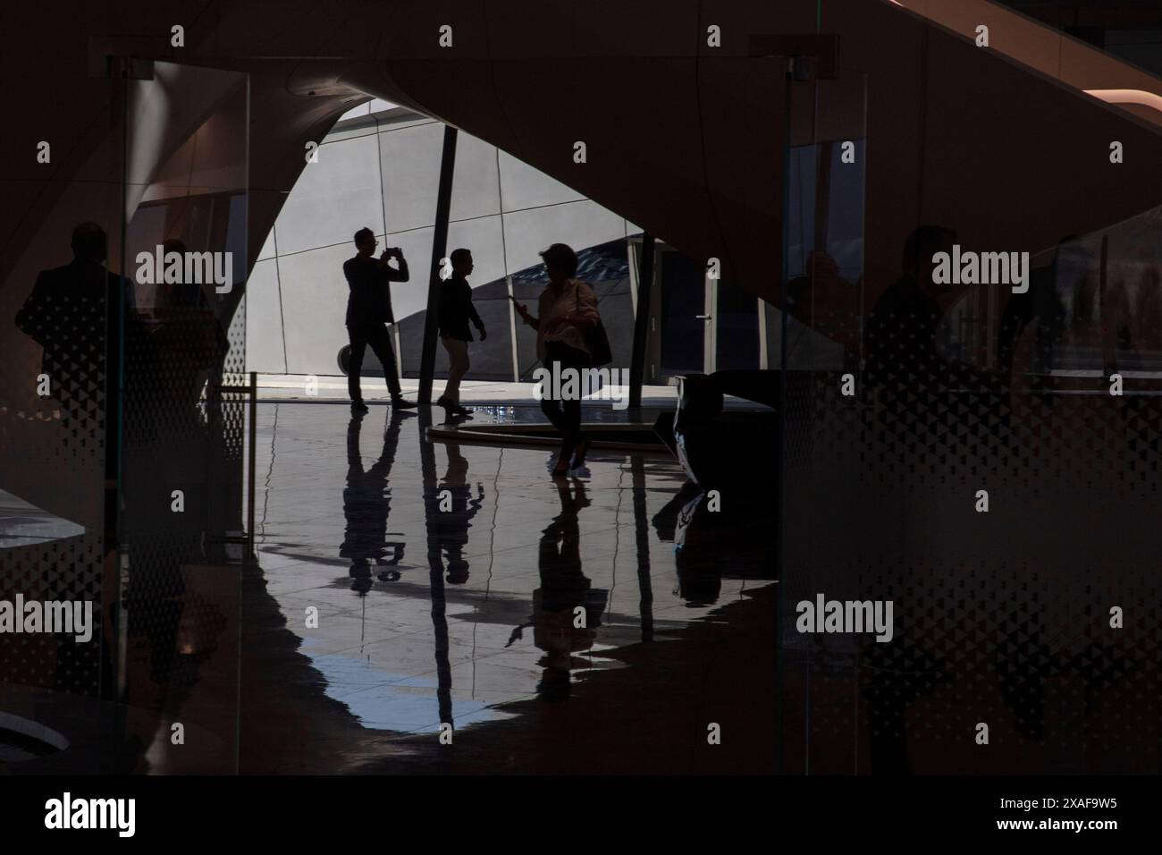 Quelqu'un marchant dans l'espace entre les bureaux et la salle de réception principale. Siège social de BEEAH, Sharjah, Émirats arabes Unis. Architecte : Zaha Banque D'Images