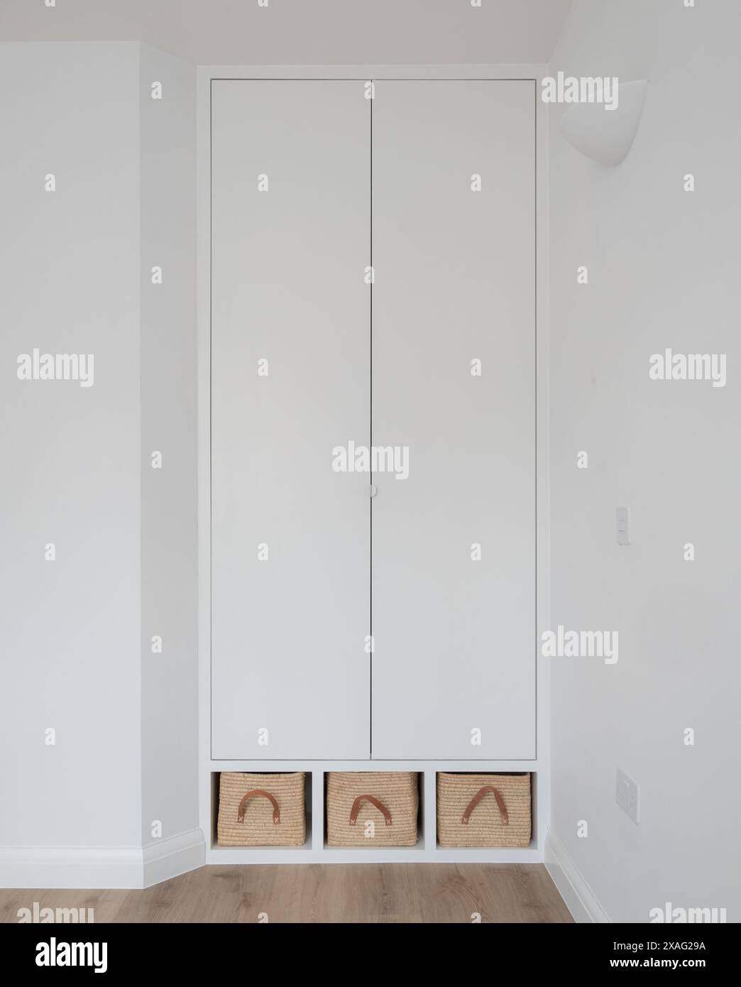 Armoires de chambre modernes en MDF peint en blanc, avec paniers en raphia. Les placards sont conçus par l'architecte dans un style simple minimaliste. Banque D'Images