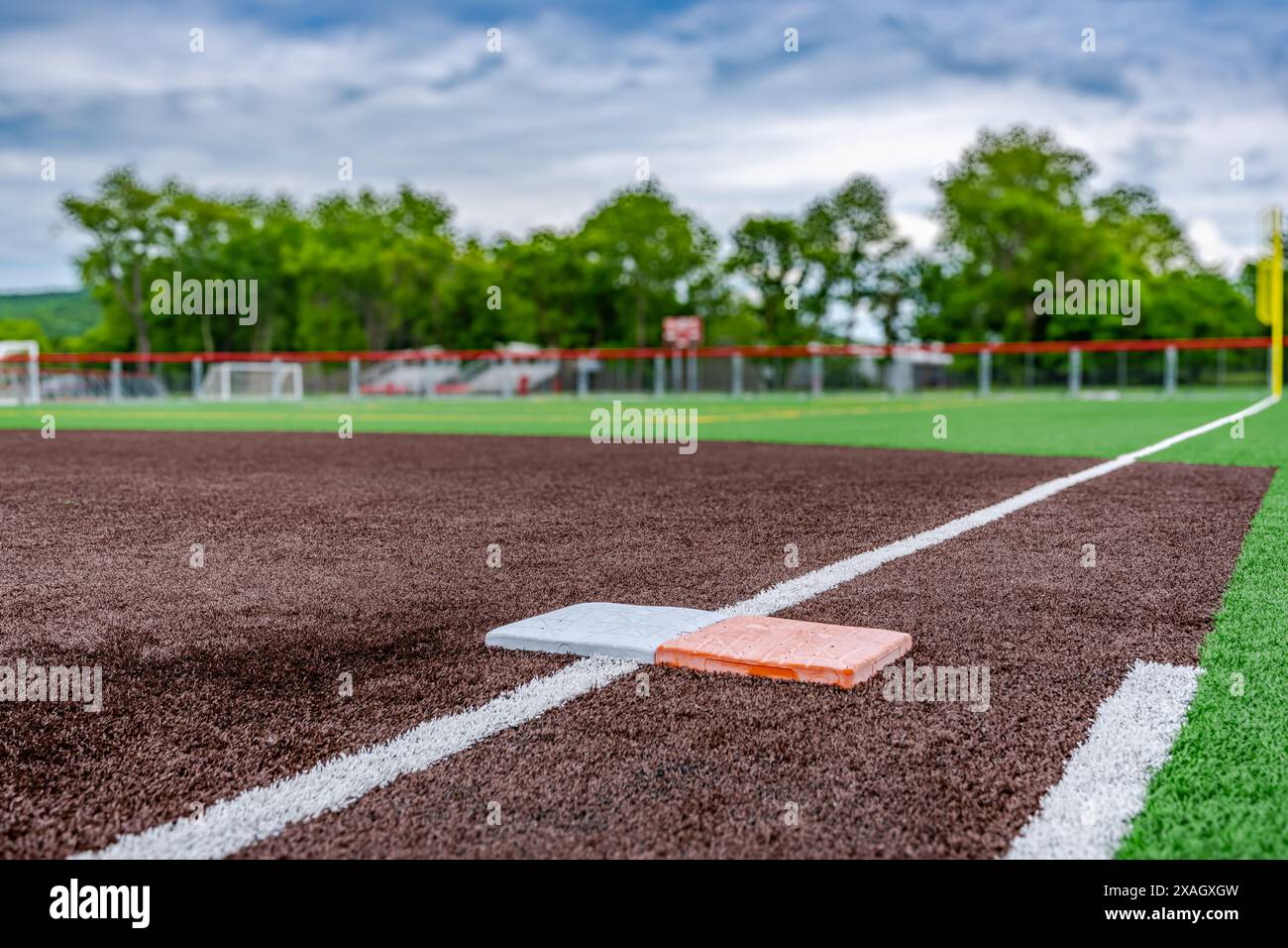 Vue du terrain de softball synthétique pour l'école secondaire, première base avec deuxième base de sécurité orange, en regardant vers la plaque d'accueil. Banque D'Images