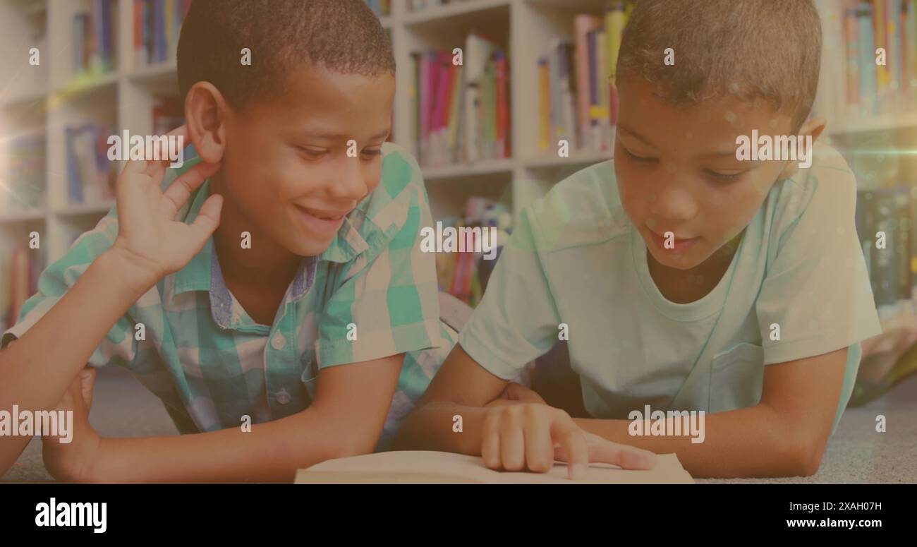 Image de traînées de lumière sur des garçons biraciaux lisant des livres Banque D'Images