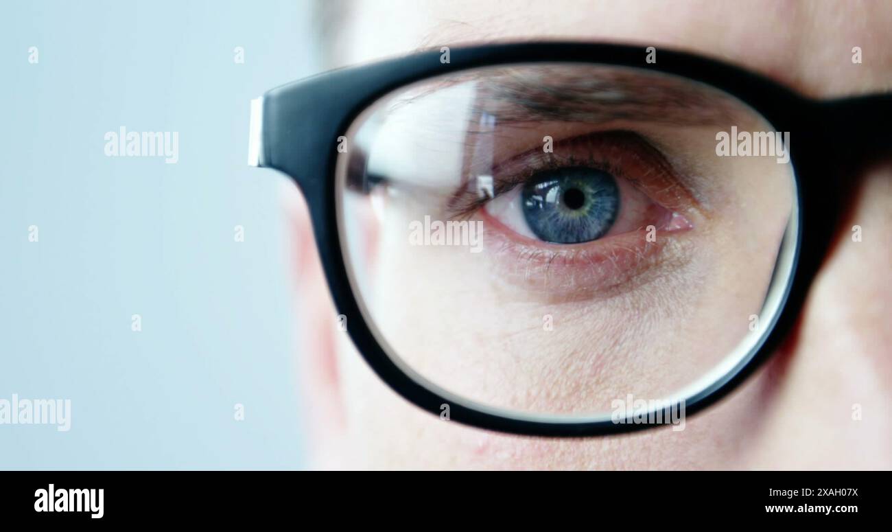 Image d'un jeune homme caucasien portant des lunettes regardant attentivement quelque chose Banque D'Images