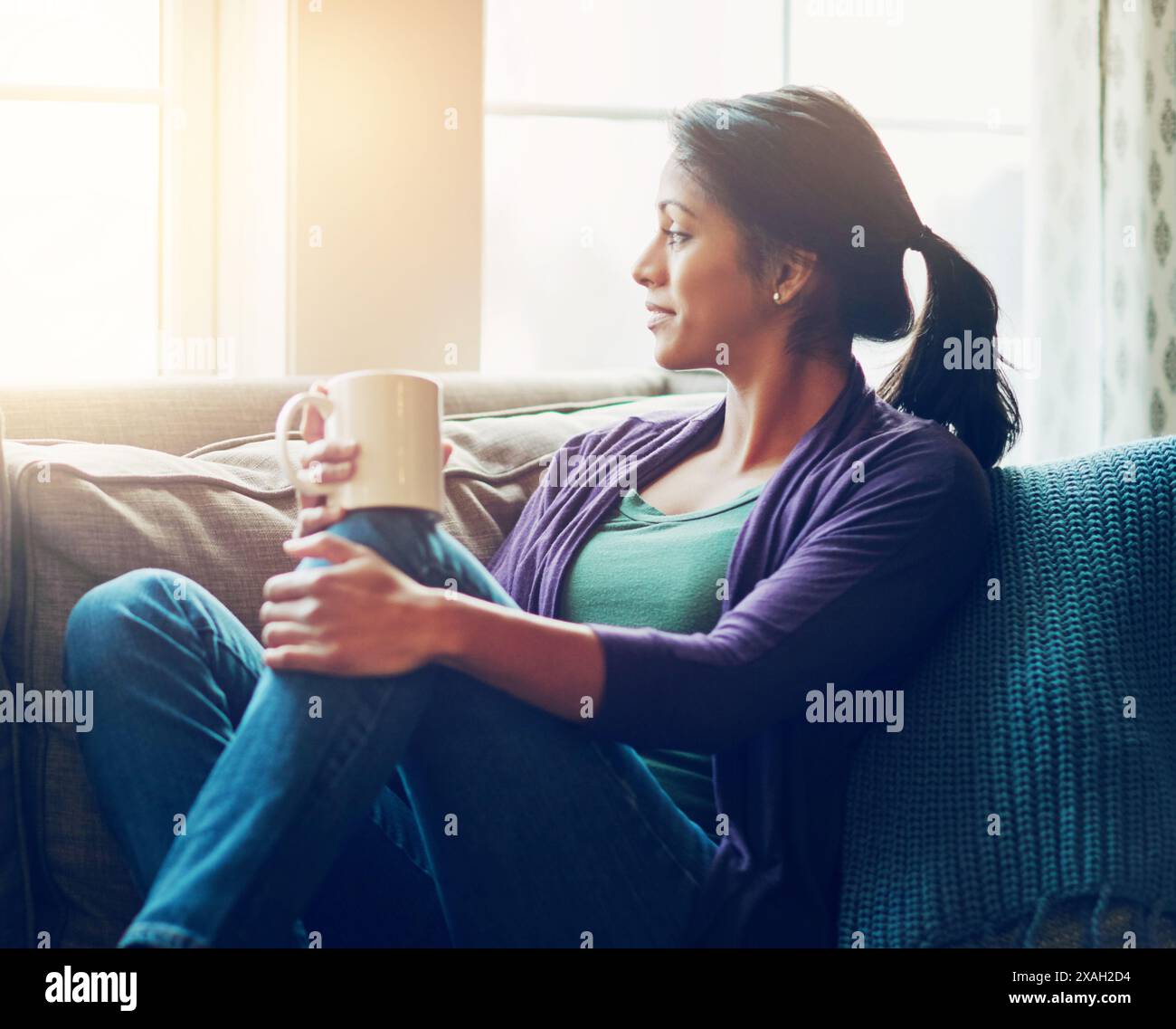 Penser, boire du café et femme indienne dans le salon de la maison pour le petit déjeuner du matin, la vision ou se souvenir. Thé, rêve et personne sur le canapé pour la paix Banque D'Images