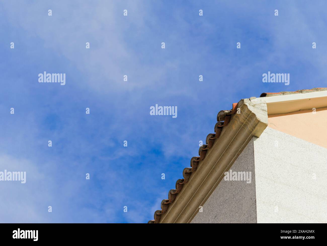 Un ciel bleu avec un toit de tuiles et un mur blanc. Copier l'espace Banque D'Images