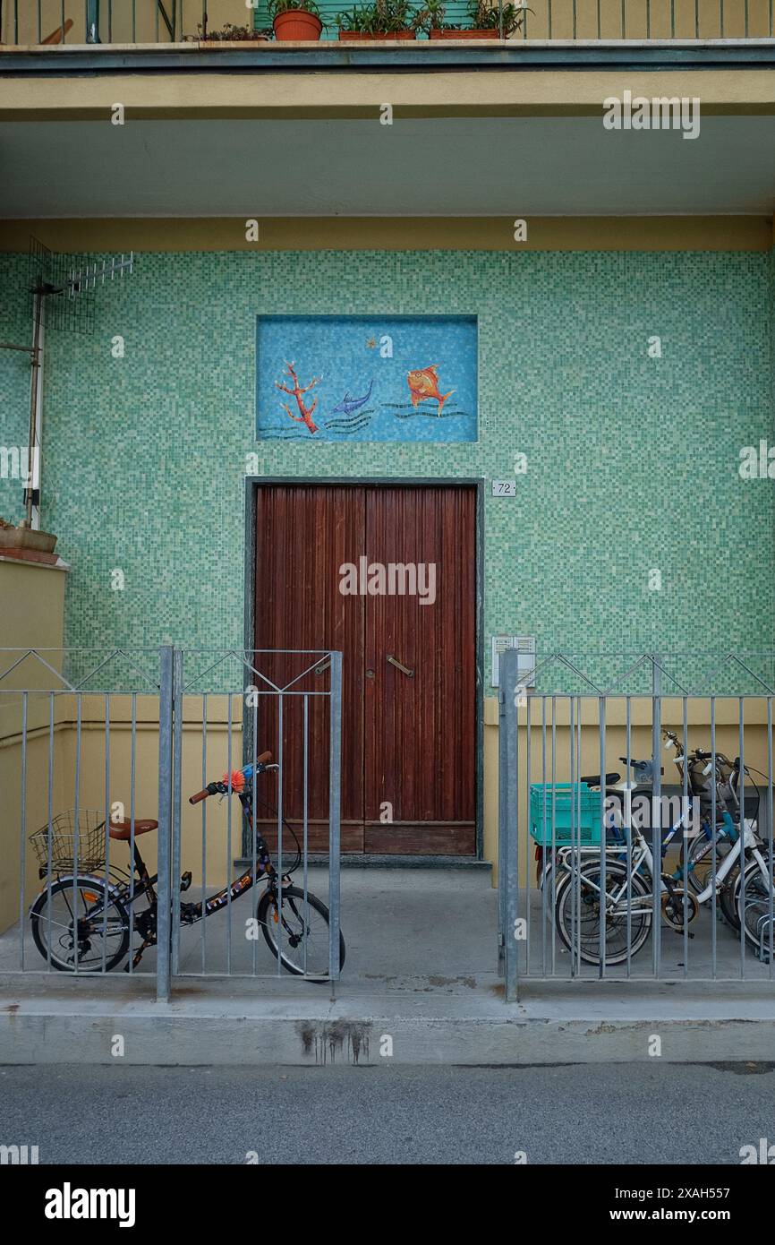 Le mur avant d'une maison en bord de mer à Monterosso al Mare, carreaux de mosaïque verte et un panneau de mosaïque sur la porte d'entrée poisson doré dans une mer bleue Banque D'Images