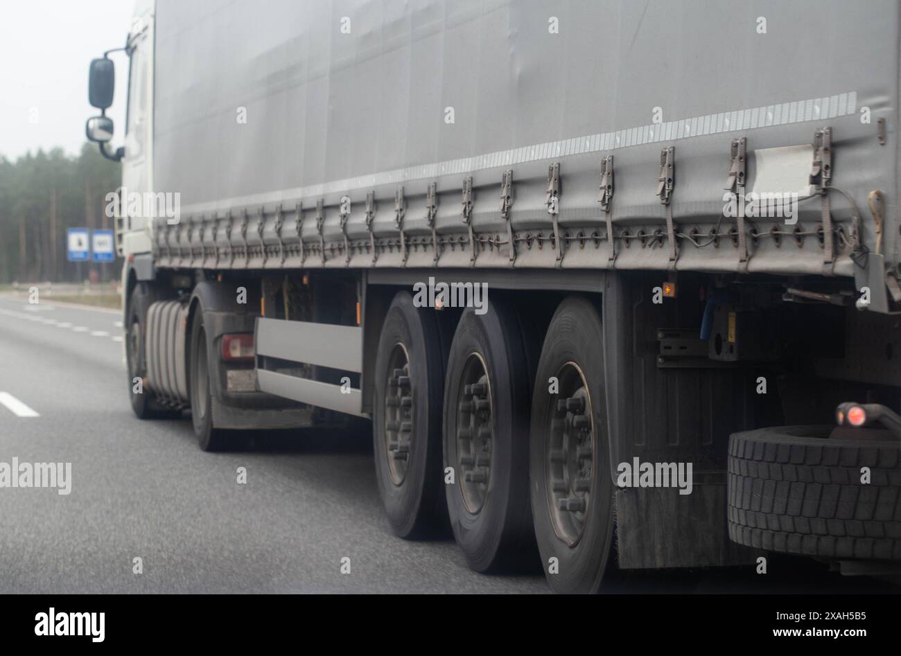 Roues avec pneus et bande de roulement sur un camion semi-remorque sur une route asphaltée. Concept de freinage d'urgence et d'usure des roues sur une remorque. Banque D'Images