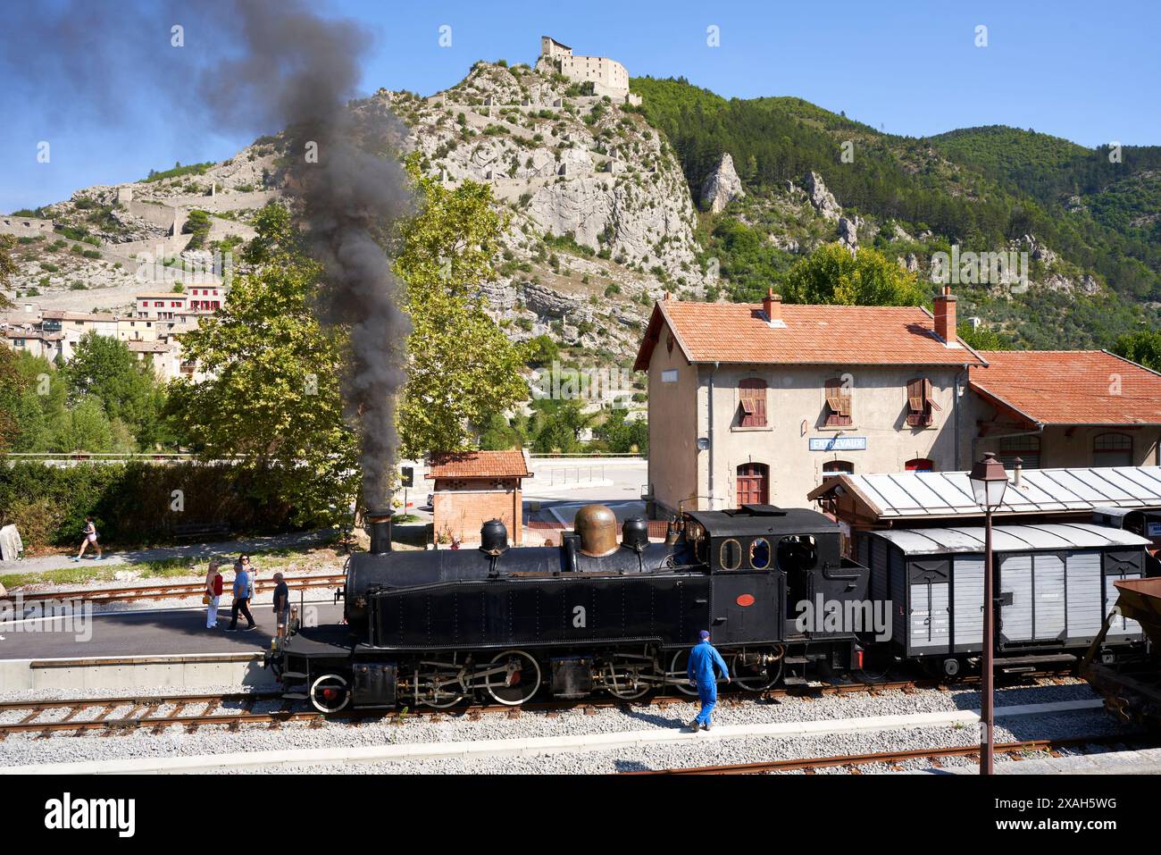 VUE AÉRIENNE depuis un mât de 6 mètres. Le train à vapeur avant le départ de la gare d'Entrevaux. Château d'Entrevaux au sommet de la falaise. France. Banque D'Images