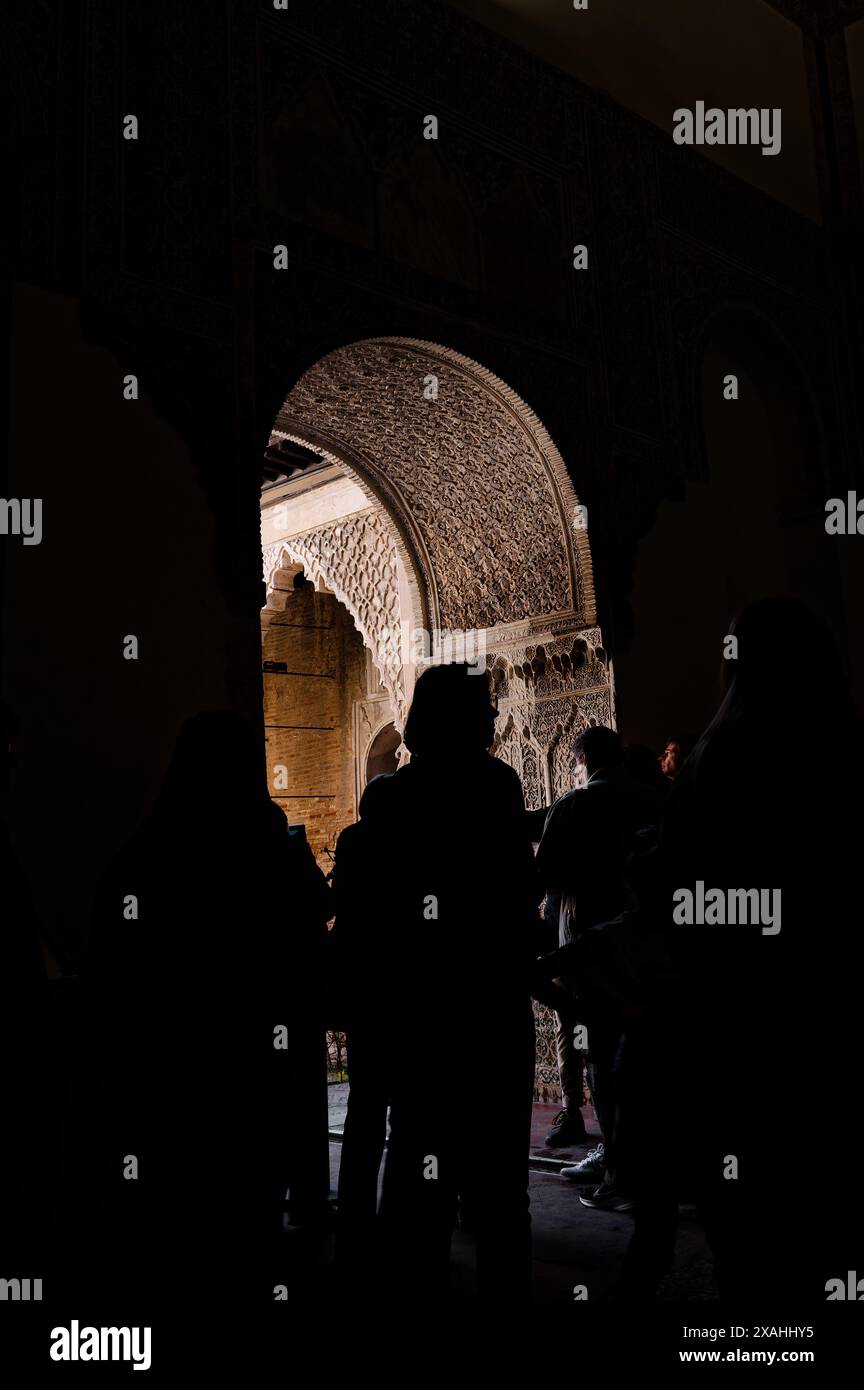 Les visiteurs se silhouaient contre les arches ornées de l'alcazar royal de séville, mettant en évidence les détails complexes de l'architecture mauresque Banque D'Images