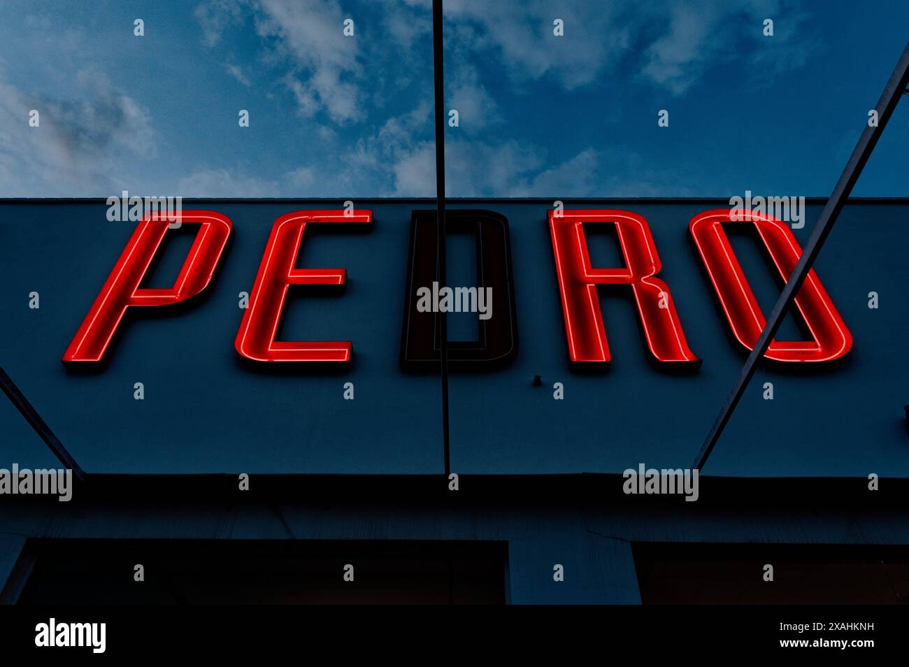 Une lettre lumineuse au néon indiquant « pedro » avec une lettre soufflée illumine un arrêt de repos sur une autoroute espagnole sur un fond sombre Banque D'Images