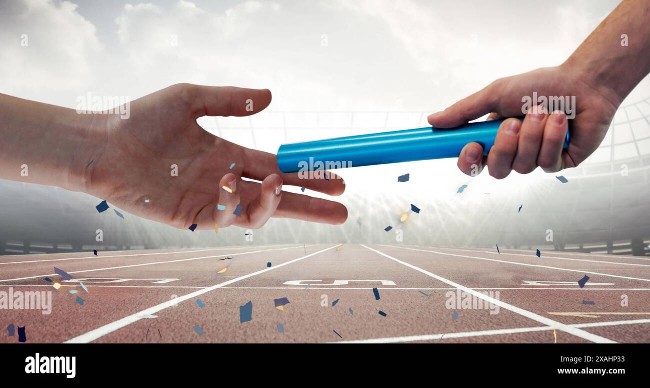 Confettis tombant sur gros plan d'une main passant un bâton contre un terrain de sport Banque D'Images