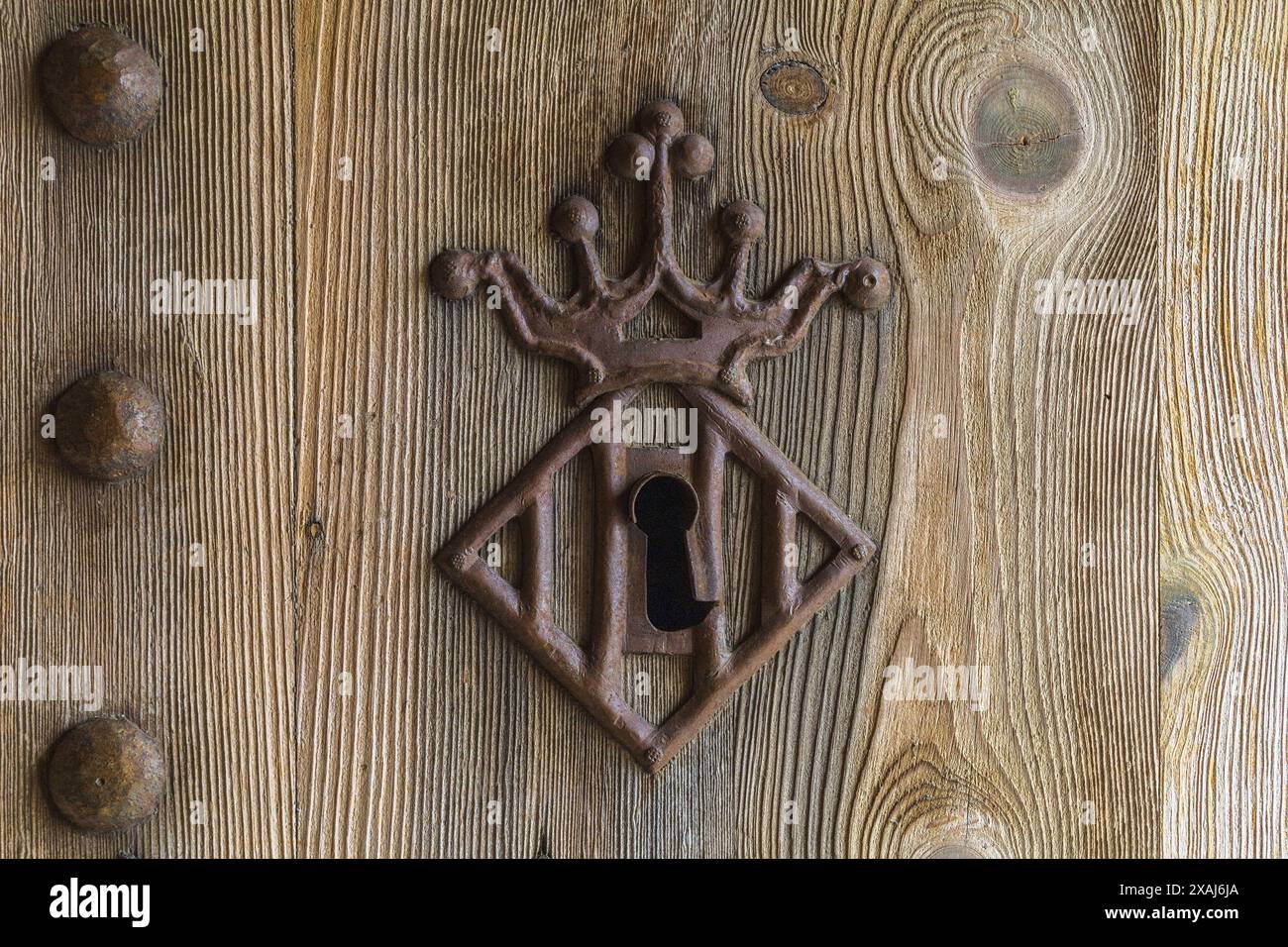 photographie à plat rapprochée d'une vieille porte texturée en bois tendre avec trou de serrure en métal rouille décoré et têtes de clous Banque D'Images