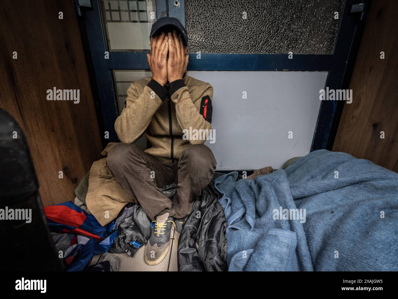 PRODUCTION - 06 mai 2024, Hesse, Francfort-sur-le-main : Amar (nom changé) est assis dans sa maison sûre dans une entrée de bâtiment dans le quartier de la gare de Francfort et tient ses mains devant son visage. L’homme de 50 ans est lui-même toxicomane, mais il a peur des agressions physiques d’autres junkies. (À dpa 'vues intérieures de Zombieland' du 08.06.2024) photo : Boris Roessler/dpa Banque D'Images