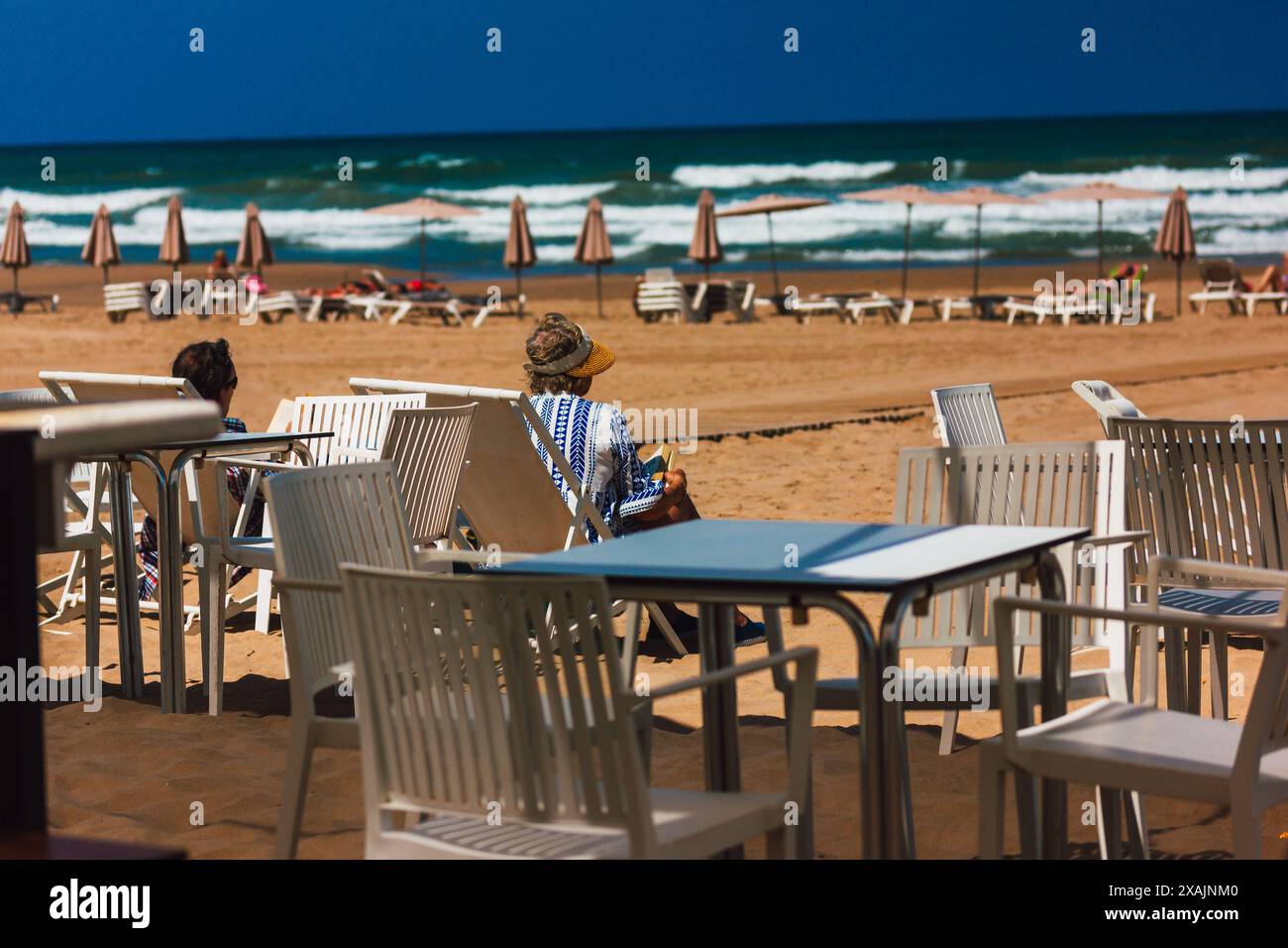 Gandia, Espagne. 1 juin 2024 scène de plage de la ville avec des gens se relaxant sur la plage, océan en été. Vacances sur la côte de la station. Terrasse de café. Banque D'Images