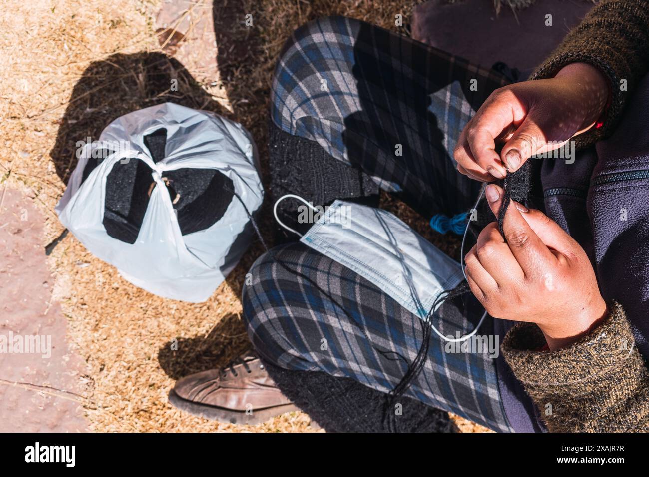Mains d'une femme andine filant de la fibre d'alpaga brune dans une roue filante ancestrale dans la cordillère des Andes dans un atelier artisanal Banque D'Images