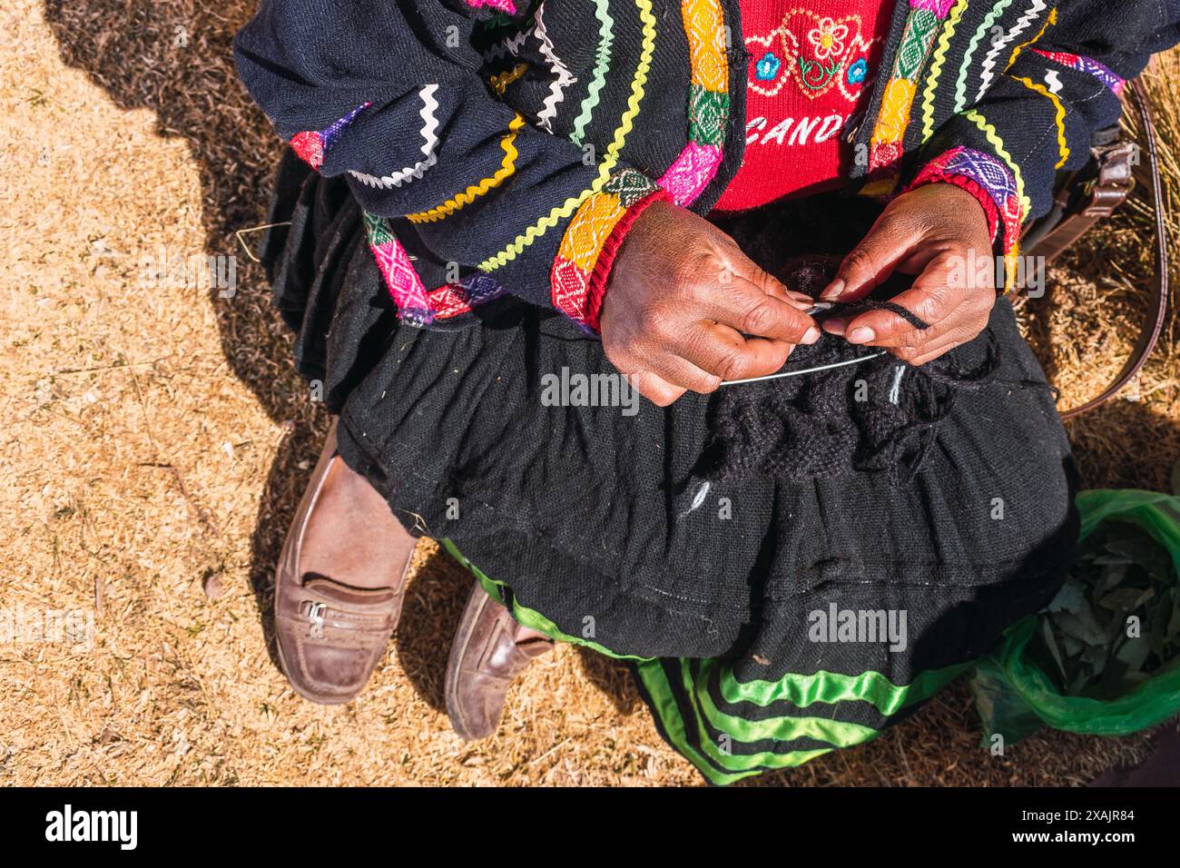 Mains d'une femme andine filant de la fibre d'alpaga brune dans une roue filante ancestrale dans la cordillère des Andes dans un atelier artisanal Banque D'Images
