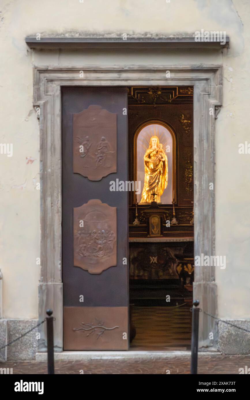 Une sculpture dorée de la vierge Marie et Jésus dans une petite église, vue à travers la porte de l'église, Italie Banque D'Images Une sculpture dorée de la vierge Marie et Jésus dans une petite église, vue à travers la porte de l'église, Italie Banque D'Images