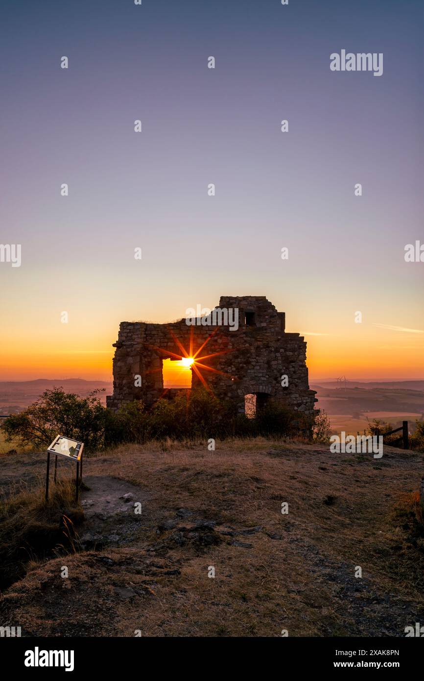 Murs du château ruines Desenberg dans le Warburger Börde, le soleil levant brille à travers l'ouverture dans le mur et forme une étoile solaire. Warburg, Höxter district, Rhénanie du Nord-Westphalie, Allemagne Banque D'Images