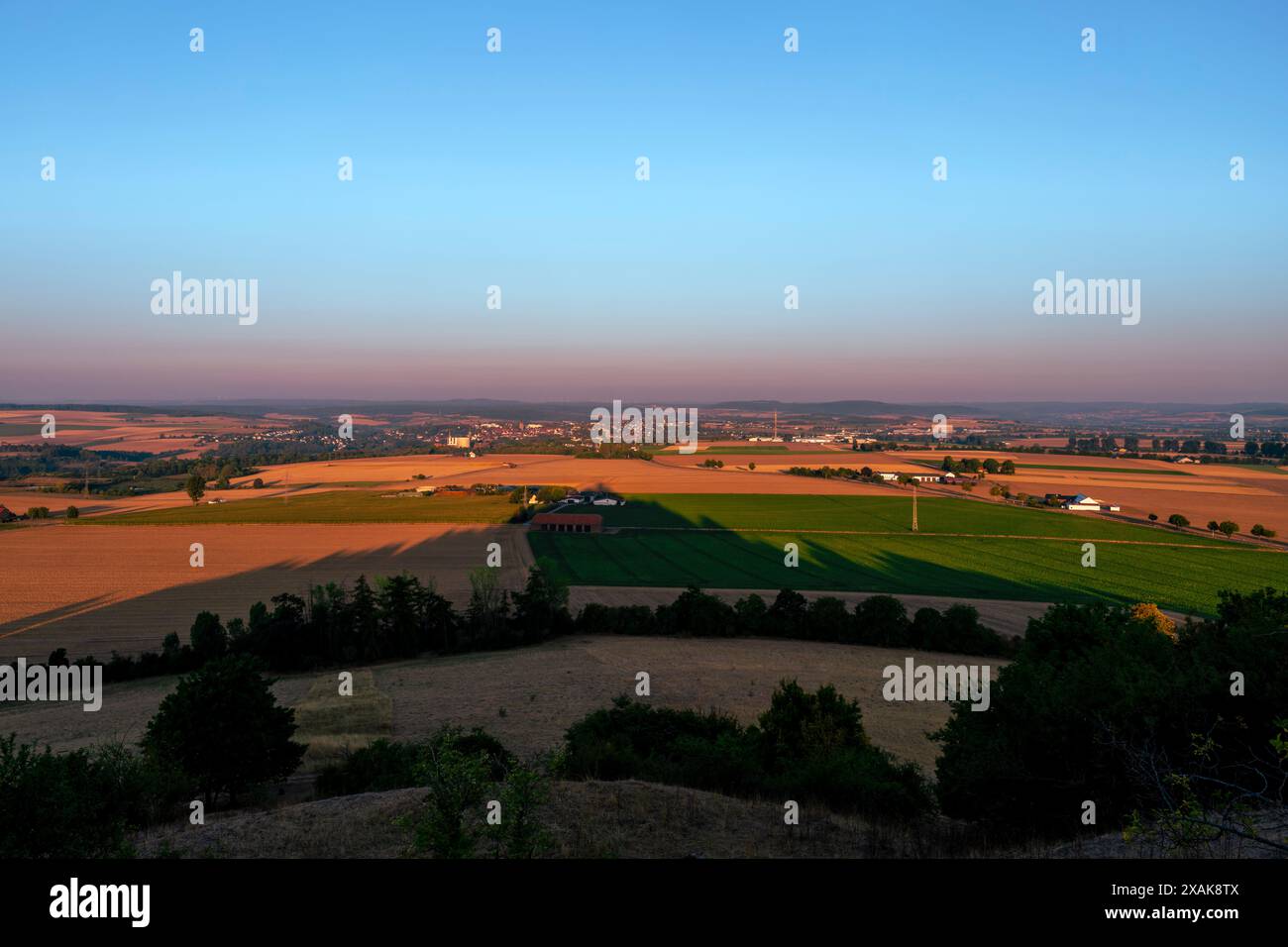 Vue de la ville de Warburg un matin d'été au lever du soleil, ombre projetée par les ruines du château de Desenberg dans le tiers inférieur de l'image, district de Höxter, Rhénanie du Nord-Westphalie, Allemagne Banque D'Images