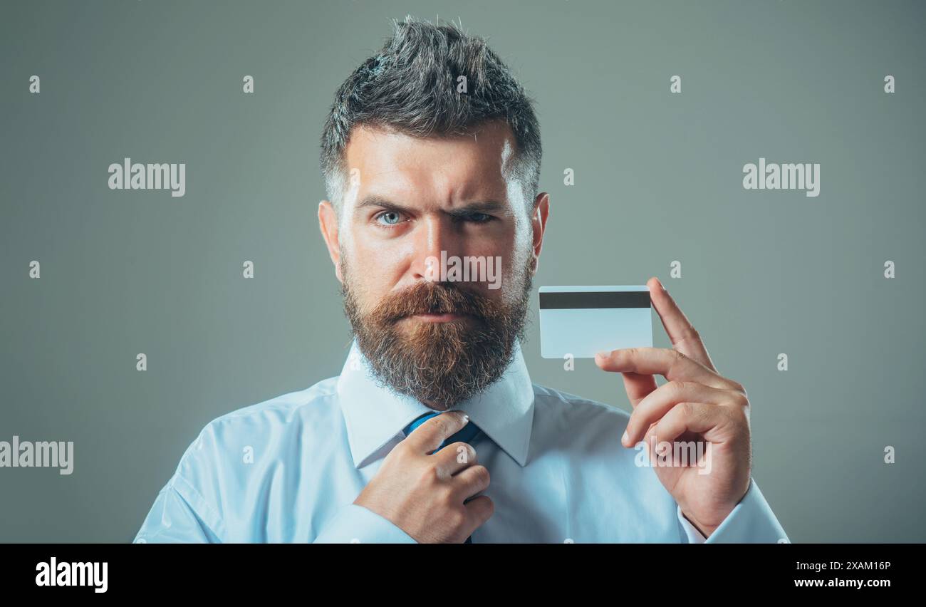 Bel homme barbu montrant une carte de crédit avec une bande magnétique. Publicité pour services bancaires, prêt ou dépôt. Homme d'affaires, financier ou banquier dans Banque D'Images
