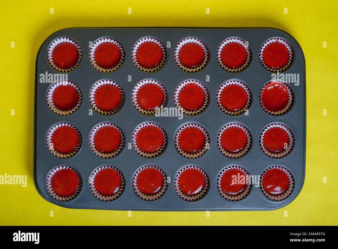 Plateau avec mélange d'ingrédients de cupcake en velours rouge prêt à cuire. Fond jaune. Banque D'Images