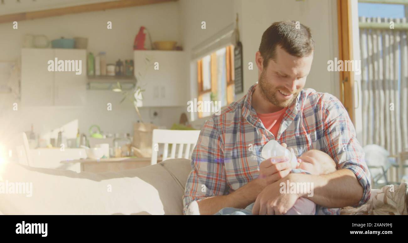 Image de taches lumineuses sur un père caucasien heureux nourrissant bébé à la maison Banque D'Images