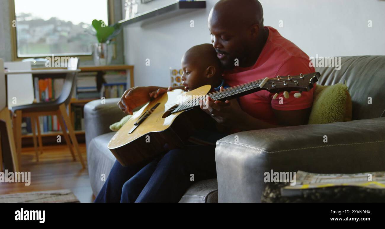 Image de taches lumineuses sur heureux père afro-américain jouant de la guitare avec son fils Banque D'Images