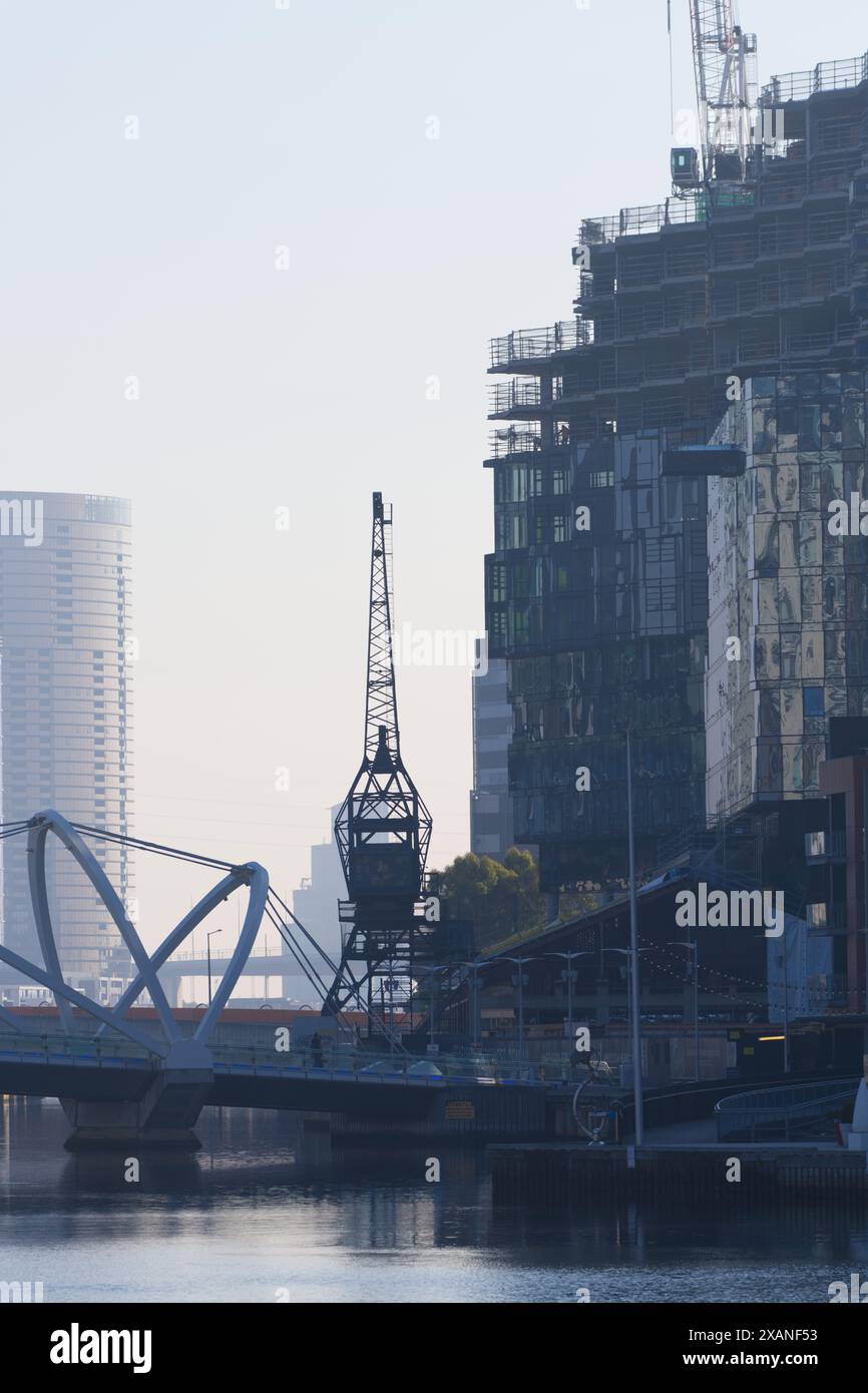 Pont sur la rivière Yarra ville de Melbourne montrant une vieille grue, un chantier de construction urbain, des gratte-ciel par un jour brumeux, Victoria, Australie. Banque D'Images