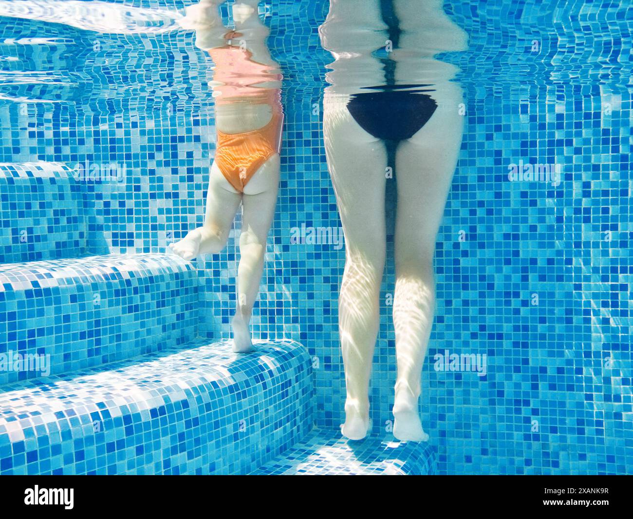 Mère et enfant dans la piscine, jambes sous-marines de la femme et de l'enfant dans l'eau de la piscine, vacances en famille Banque D'Images