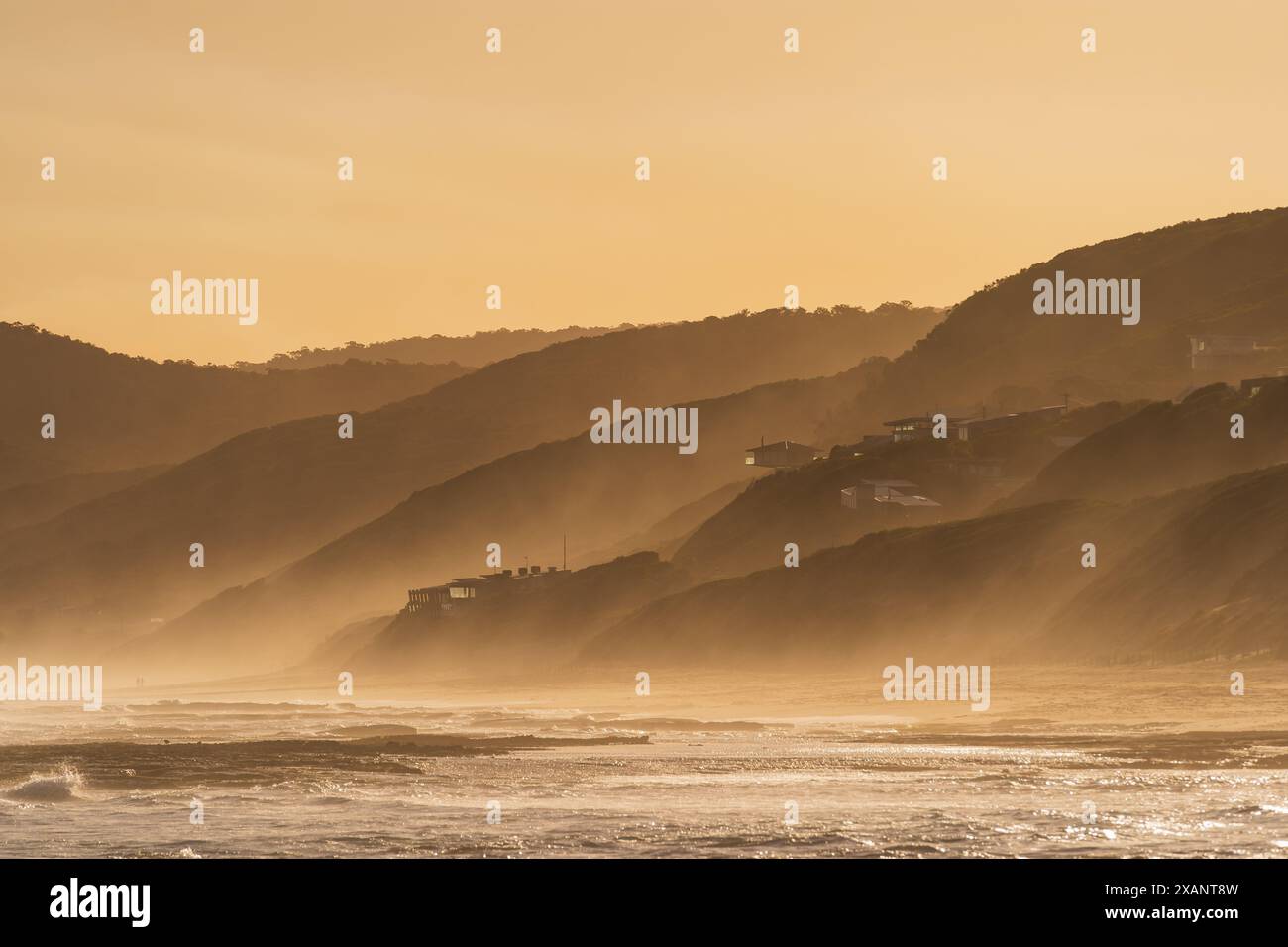 Vue lointaine brouillard marin couvrant une côte vallonnée dans la lumière dorée à Fairhaven sur la Great Ocean Road à Victoria, Australie Banque D'Images