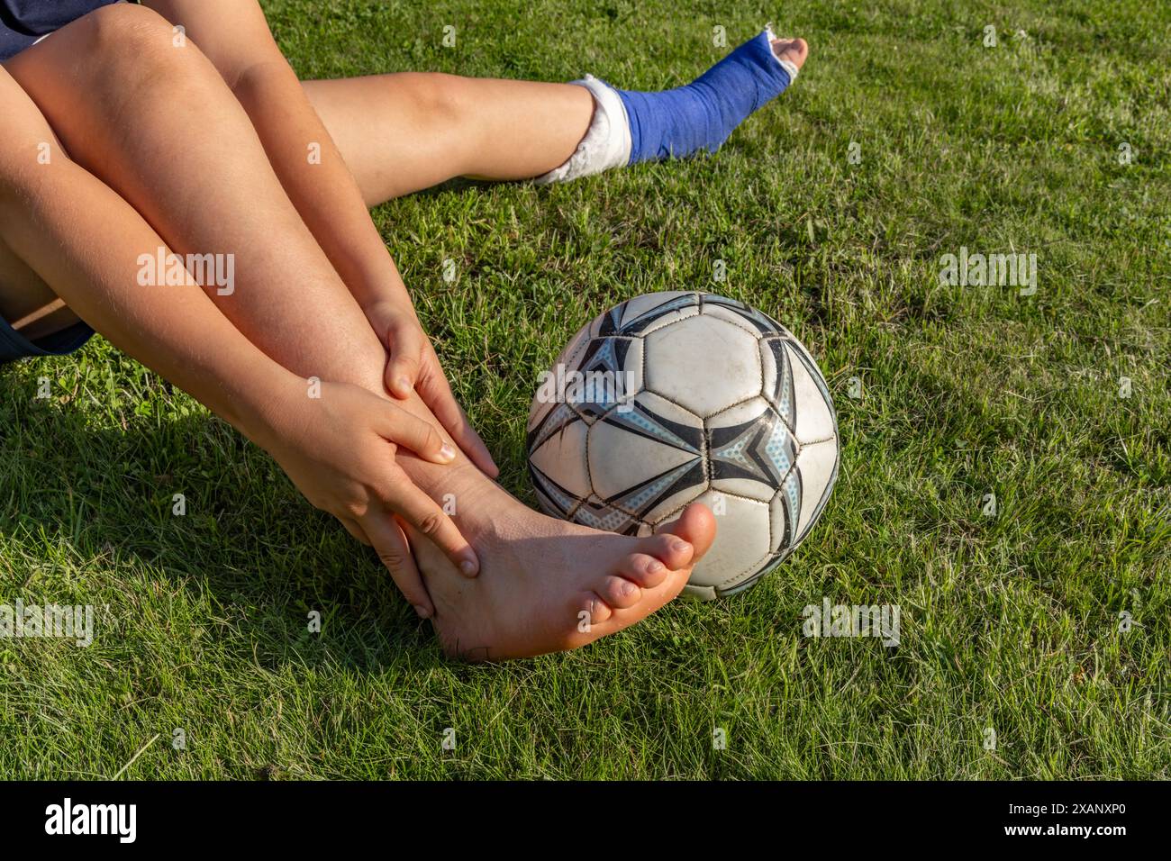 Garçon avec une jambe cassée dans un plâtre pendant un match de football une blessure à un jeune athlète Banque D'Images