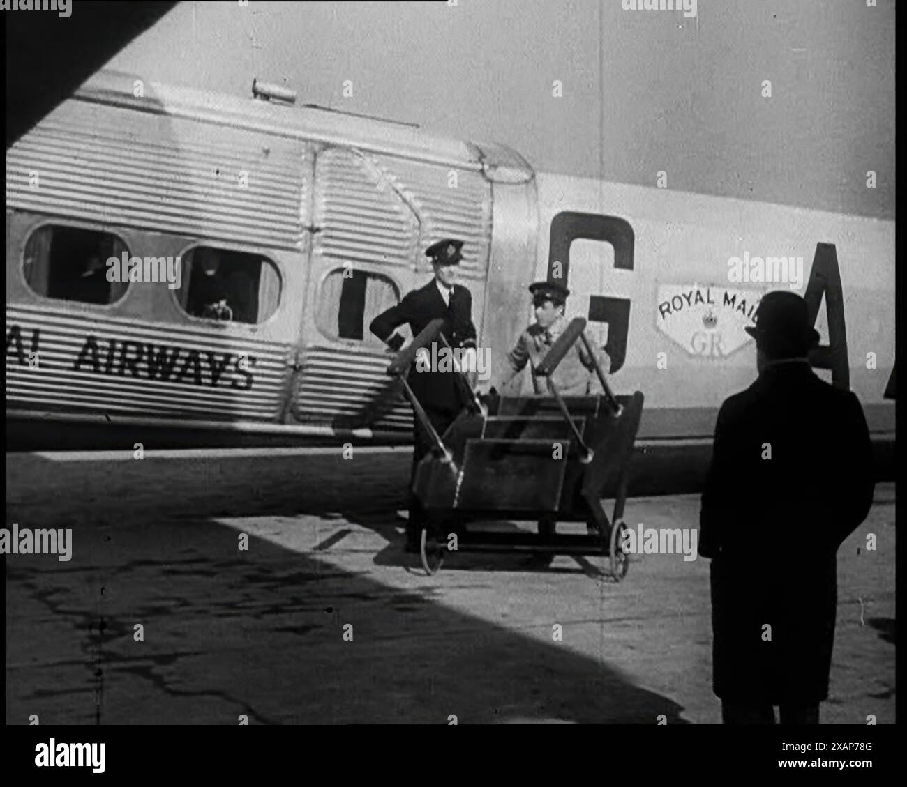 Trois hommes tendre vers un avion au sol, 1933. Avion emmenant le premier ministre britannique Ramsay MacDonald à Genève pour la Société des Nations. De "Time to Remember - The Time of the Monster", 1933 (bobine 2) ; film documentaire sur les événements de 1933, la montée de Roosevelt et Hitler. Banque D'Images