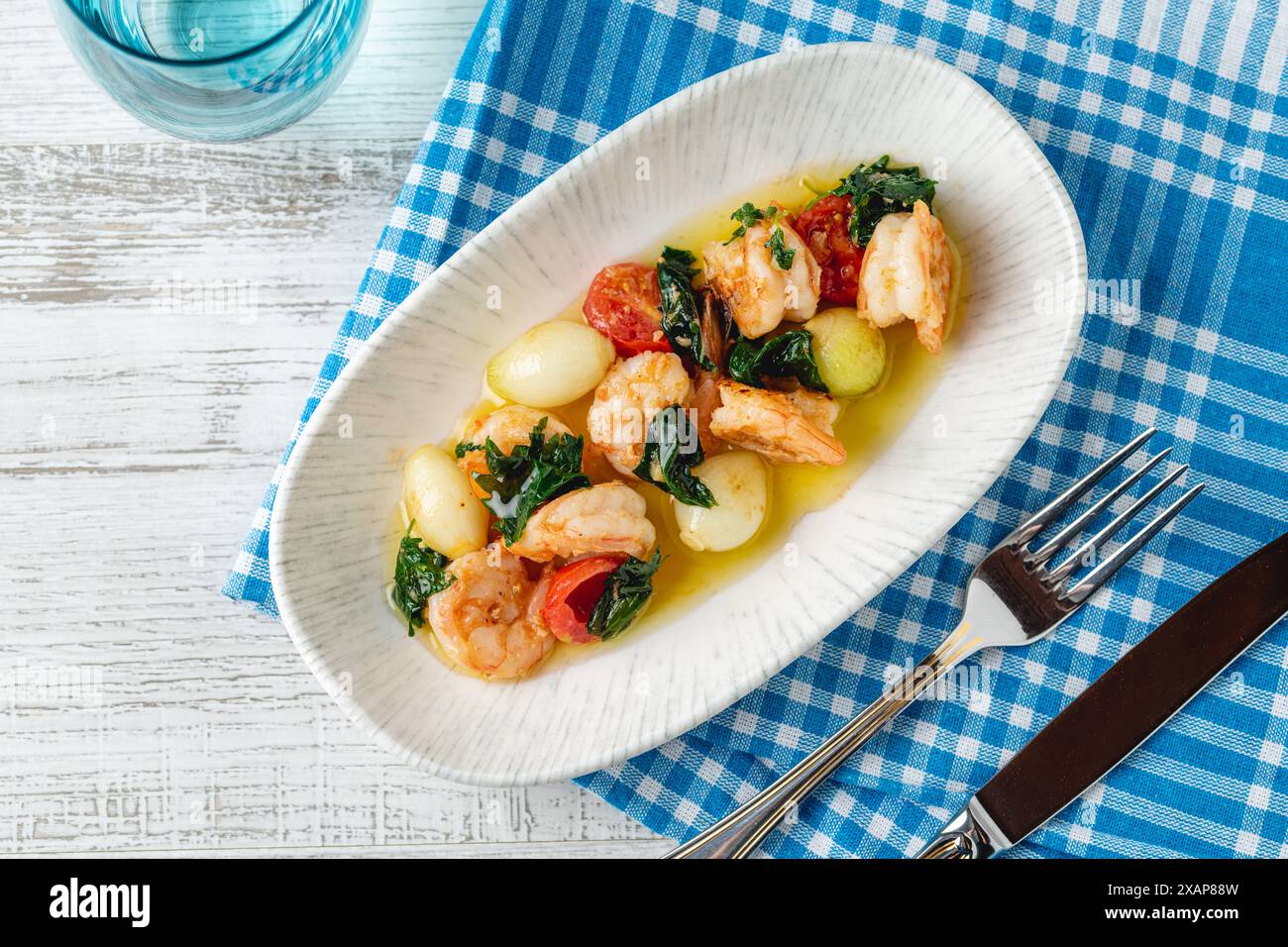 Apéritif avec des crevettes, des oignons et des tomates sur une assiette en porcelaine blanche Banque D'Images