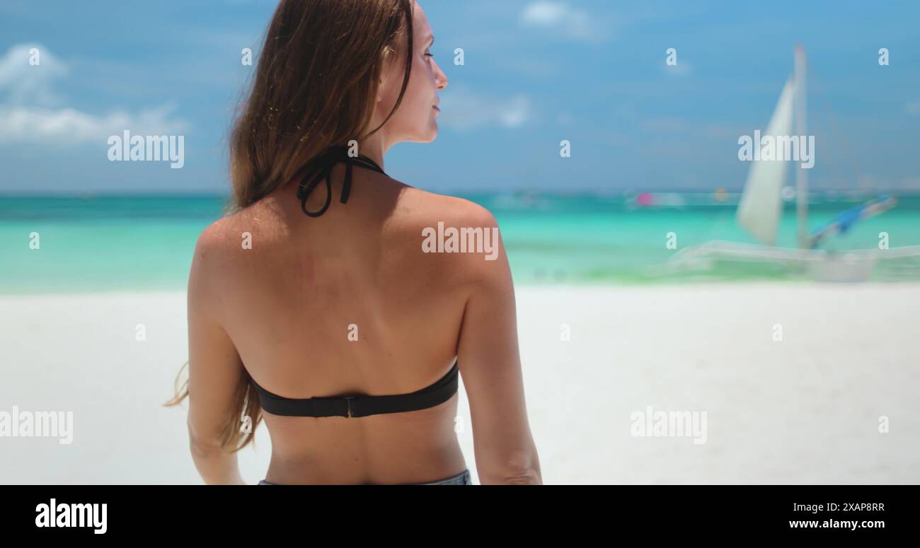 Femme en bikini marche sur la plage de sable blanc sur l'île tropicale de Boracay, Philippines. La vue arrière de fille caucasienne à cheveux longs profite du paysage de la nature sauvage, de l'eau turquoise et du ciel bleu. Voyages, tourisme, vacances Banque D'Images