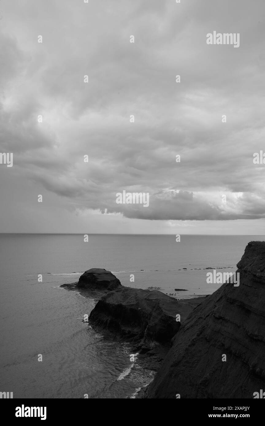 image monotone en noir et blanc du promontoire côtier et du ciel nuageux et de la mer au large des côtes britanniques Banque D'Images
